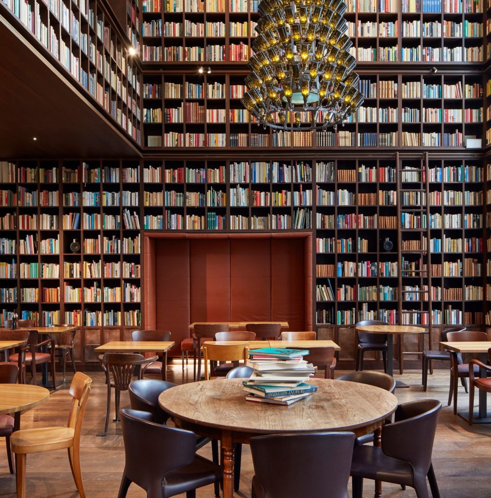 2-Geschoss hohe Bibliothek mit raumhohen Bücherregalen und Kronleuchter aus Weinflaschen.