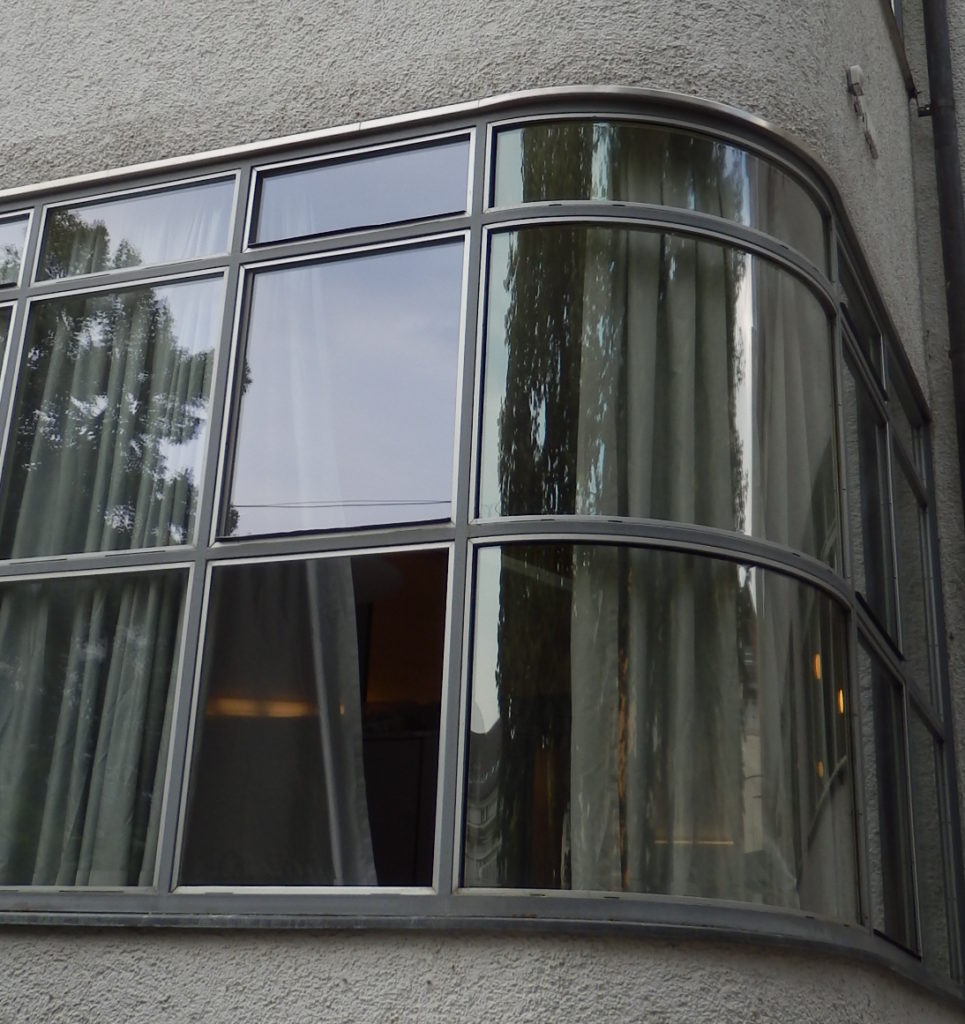 Übereck-Fenster des Hallenbades, gekrümmte Glasscheiben in Metallrahmen.